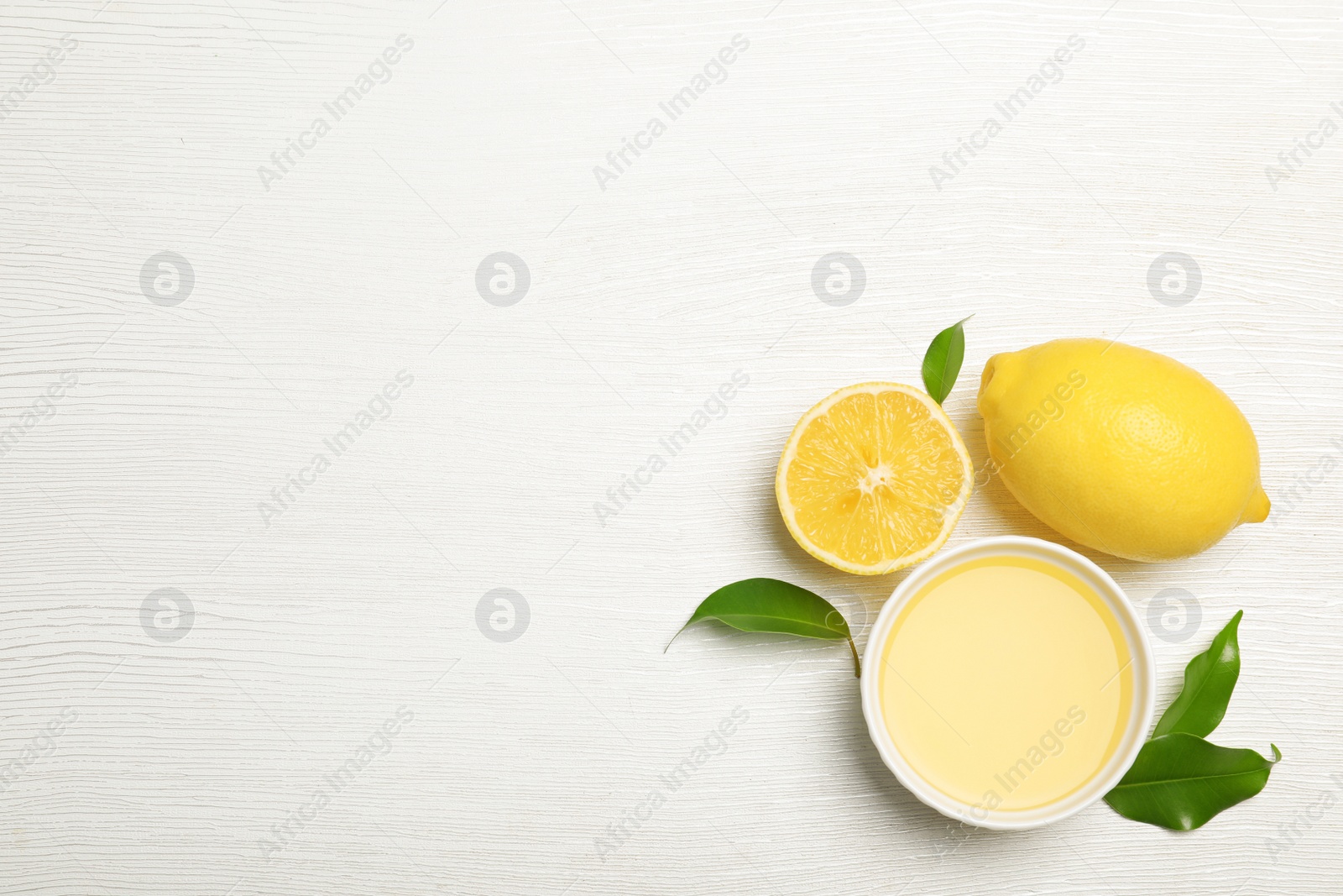 Photo of Composition with freshly squeezed lemon juice and space for text on white wooden background