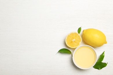 Photo of Composition with freshly squeezed lemon juice and space for text on white wooden background