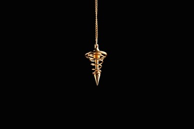 Photo of Beautiful golden pendulum with chain on black background. Hypnosis session