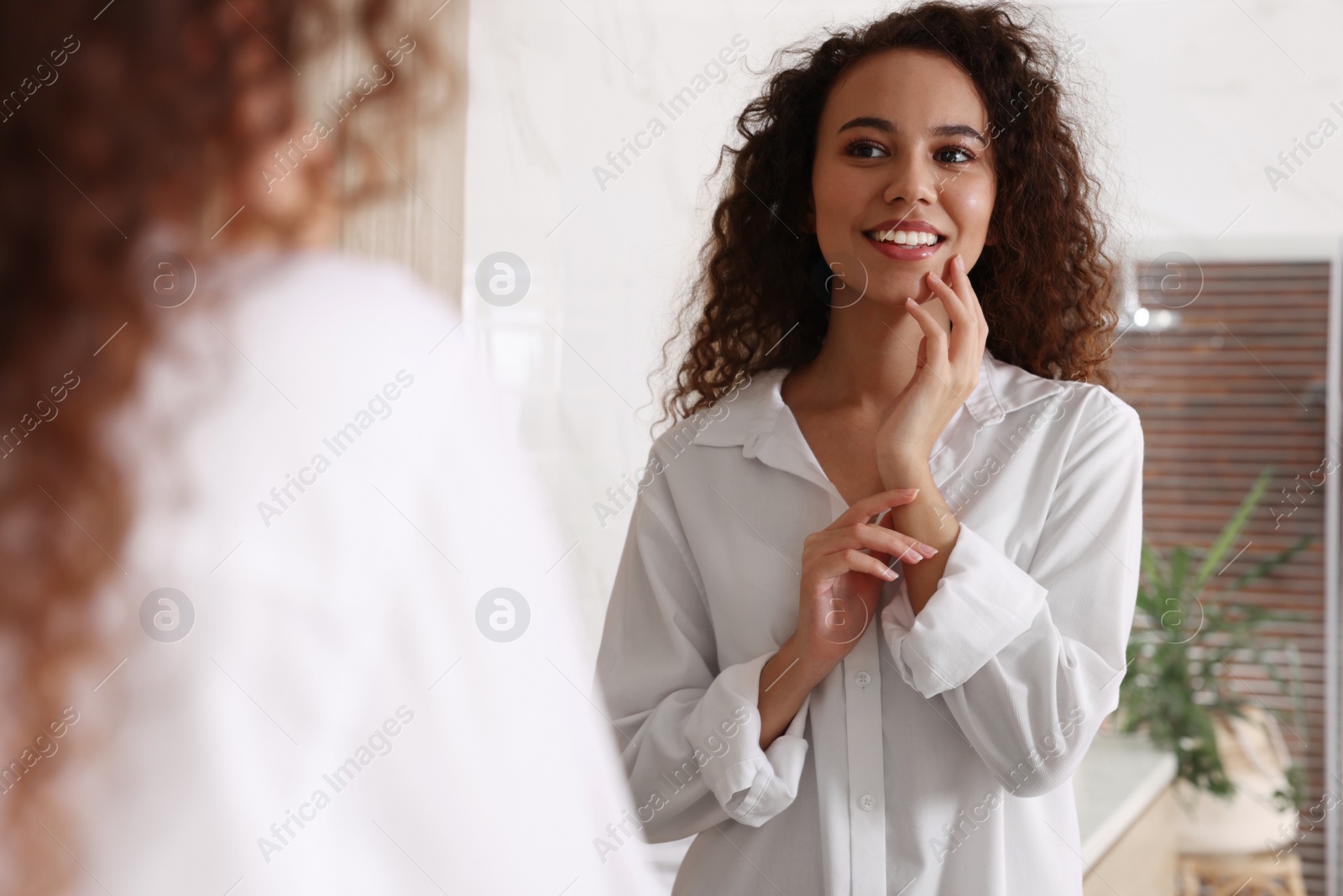 Photo of Beautiful African American woman near mirror in bathroom