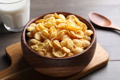 Photo of Bowl of tasty crispy corn flakes on wooden table, closeup