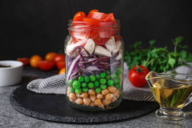 Photo of Healthy salad in glass jar on grey table