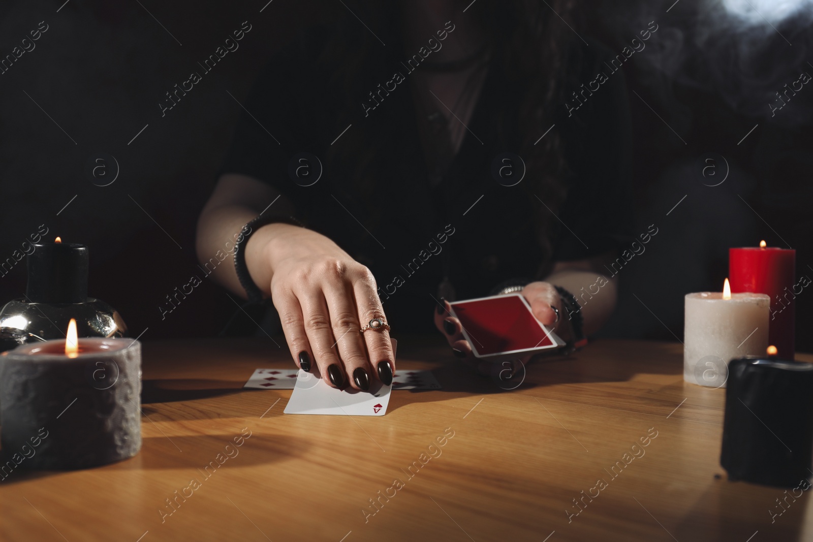 Photo of Soothsayer predicting future with cards at table indoors, closeup