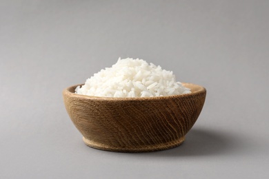 Photo of Bowl of tasty cooked rice on grey background