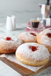 Photo of Delicious donuts with jam and powdered sugar on wooden board, closeup. Space for text