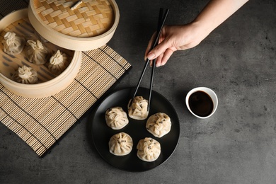 Photo of Woman eating baozi dumplings at table, top view