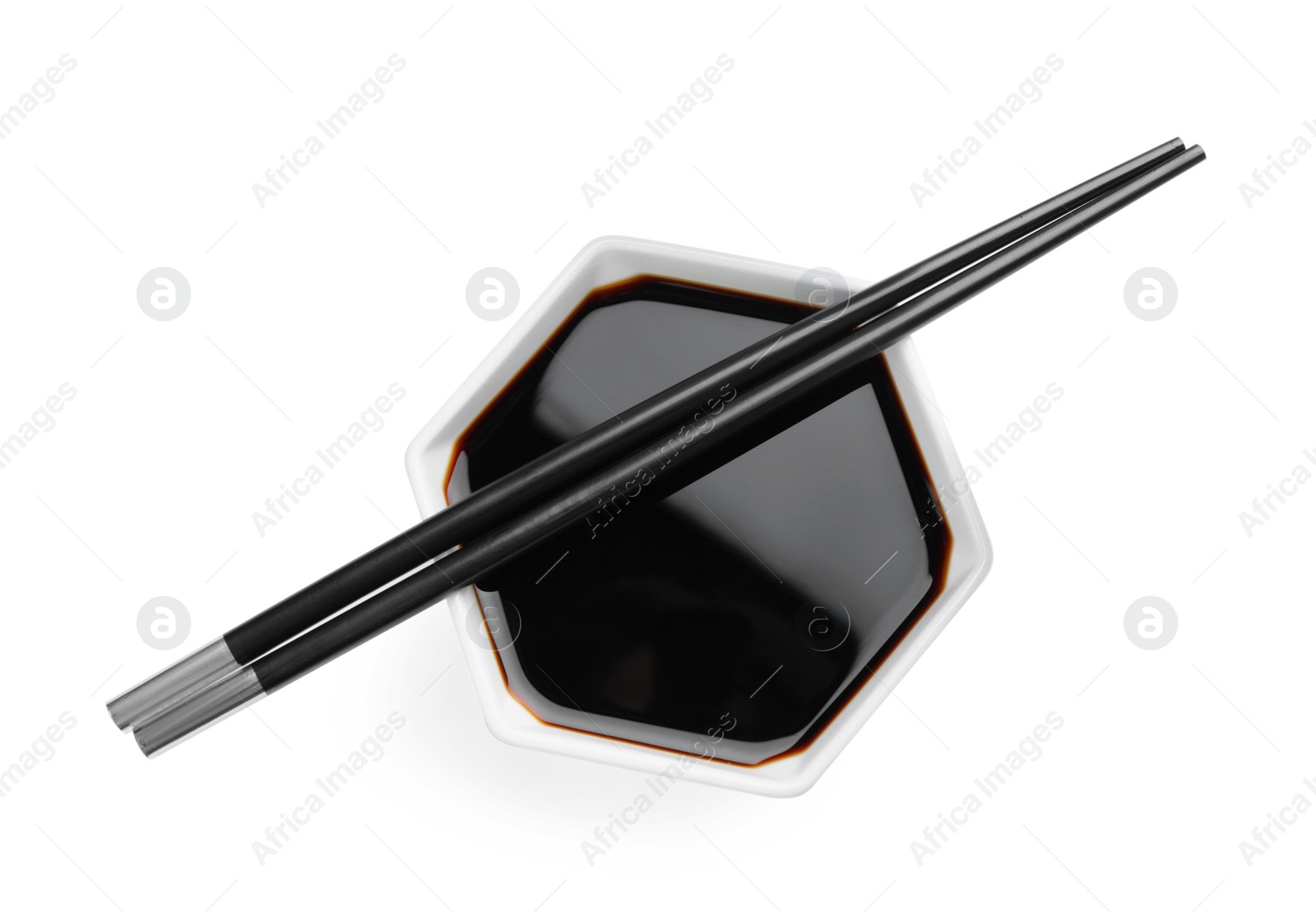 Photo of Bowl of soy sauce with chopsticks on white background, top view