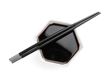 Bowl of soy sauce with chopsticks on white background, top view