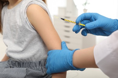 Photo of Doctor giving injection to little girl in hospital, closeup. Immunization concept