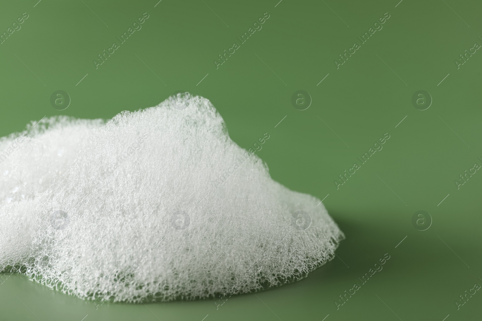 Photo of Fluffy bath foam on olive background, closeup. Space for text
