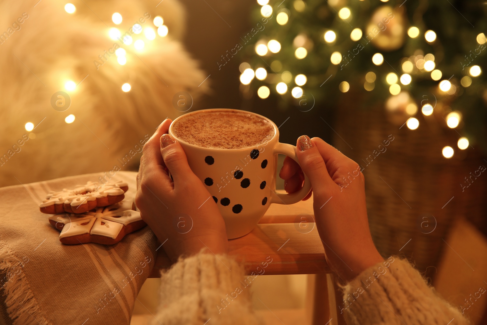 Photo of Woman with cup of hot drink and Christmas cookies at home, closeup