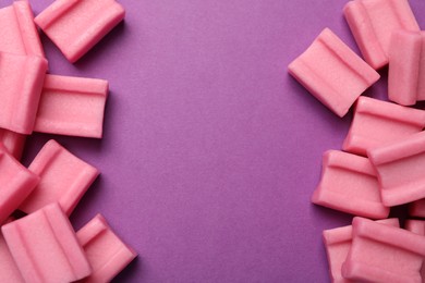 Photo of Tasty pink chewing gums on purple background, flat lay. Space for text