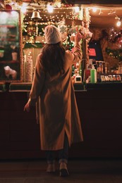Young woman spending time at Christmas fair, back view