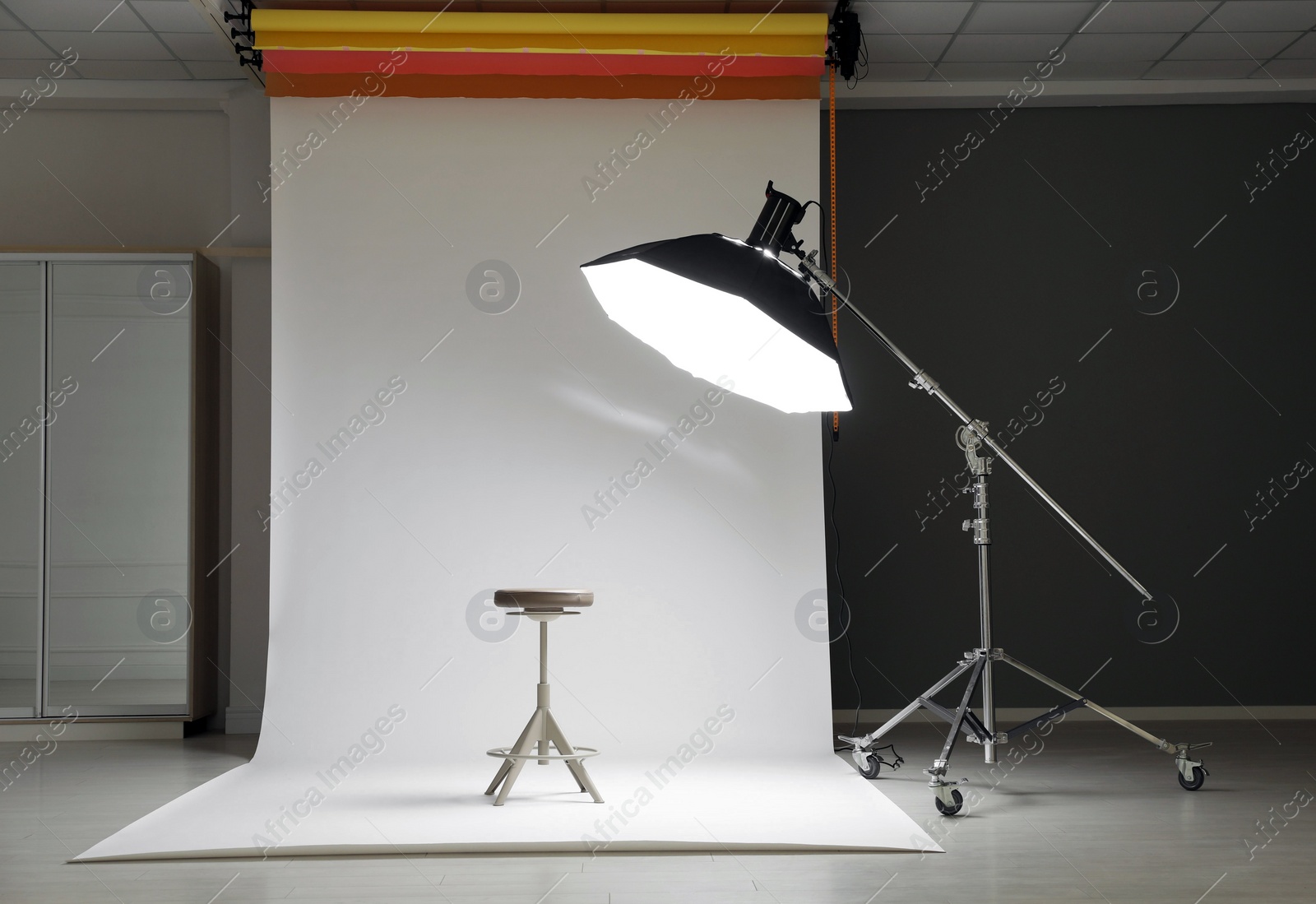 Photo of White photo background, stool and professional lighting equipment in modern studio