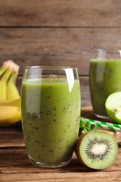 Photo of Delicious kiwi smoothie and fresh fruits on wooden table