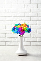 Photo of Vase with amazing rainbow rose flowers on table