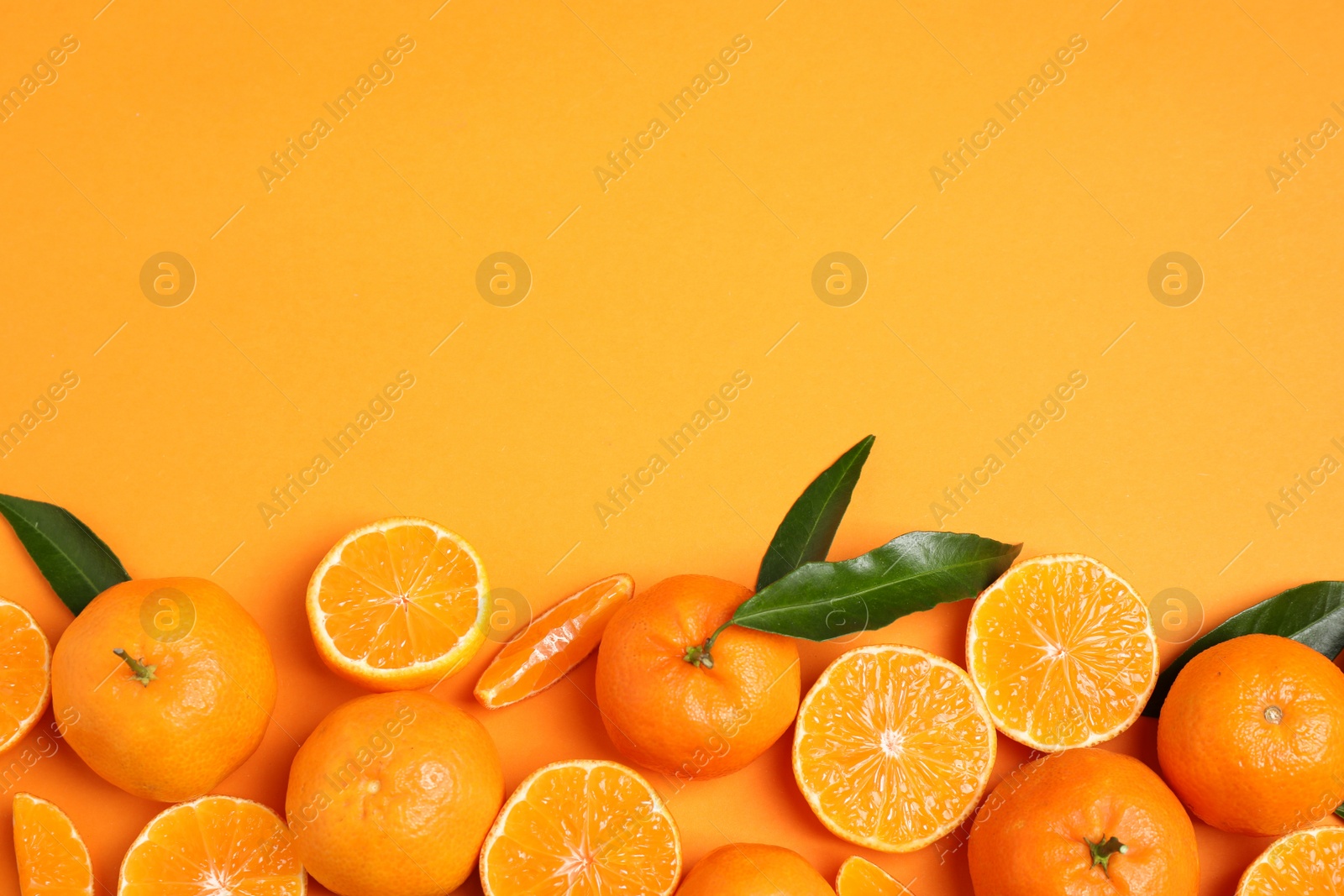 Photo of Flat lay composition with fresh ripe tangerines and space for text on orange background. Citrus fruit