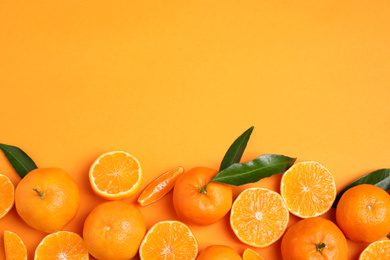 Photo of Flat lay composition with fresh ripe tangerines and space for text on orange background. Citrus fruit