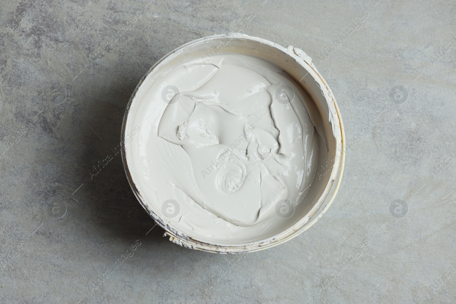 Photo of Bucket with plaster on concrete floor, top view