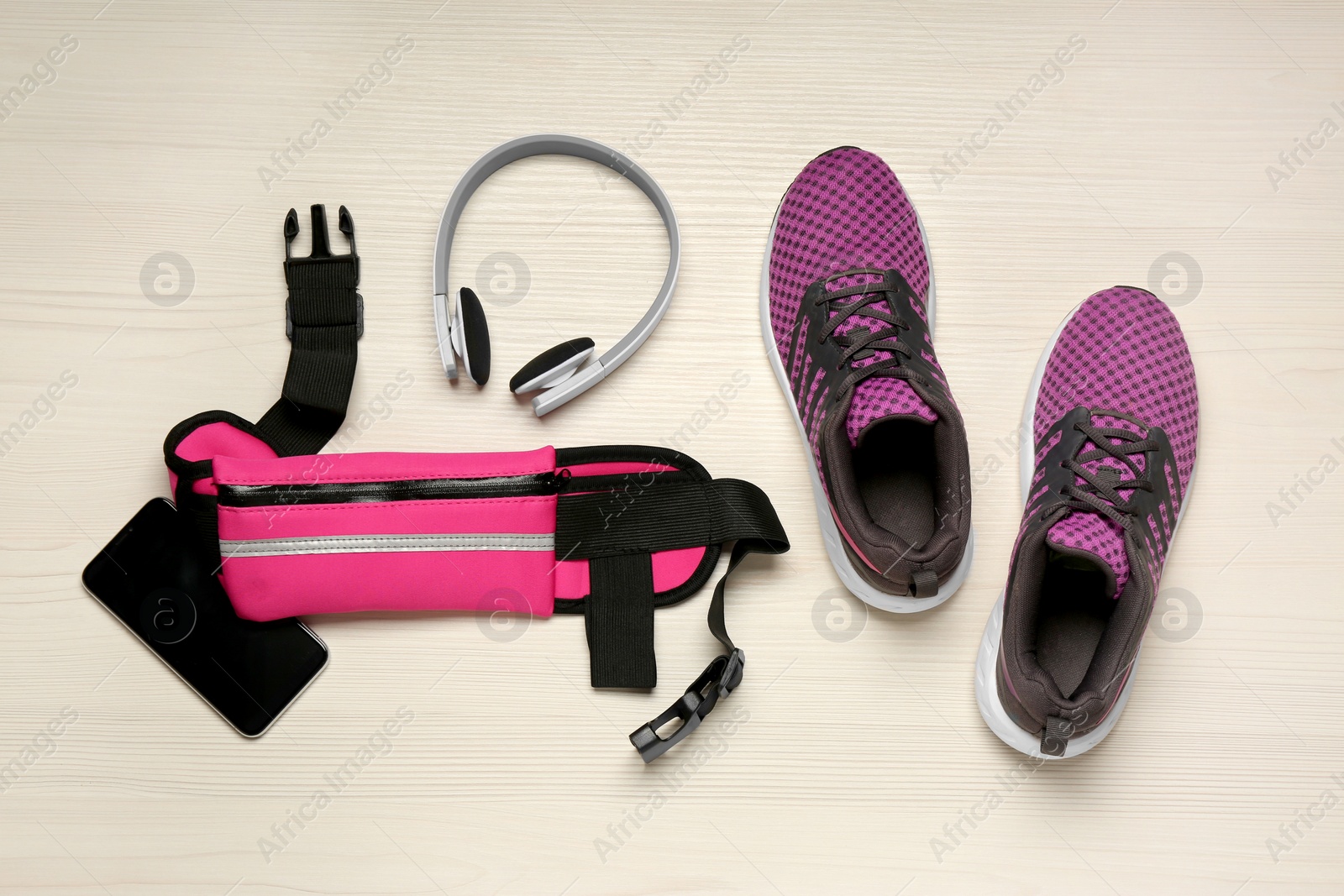 Photo of Flat lay composition with pink waist bag on white wooden table