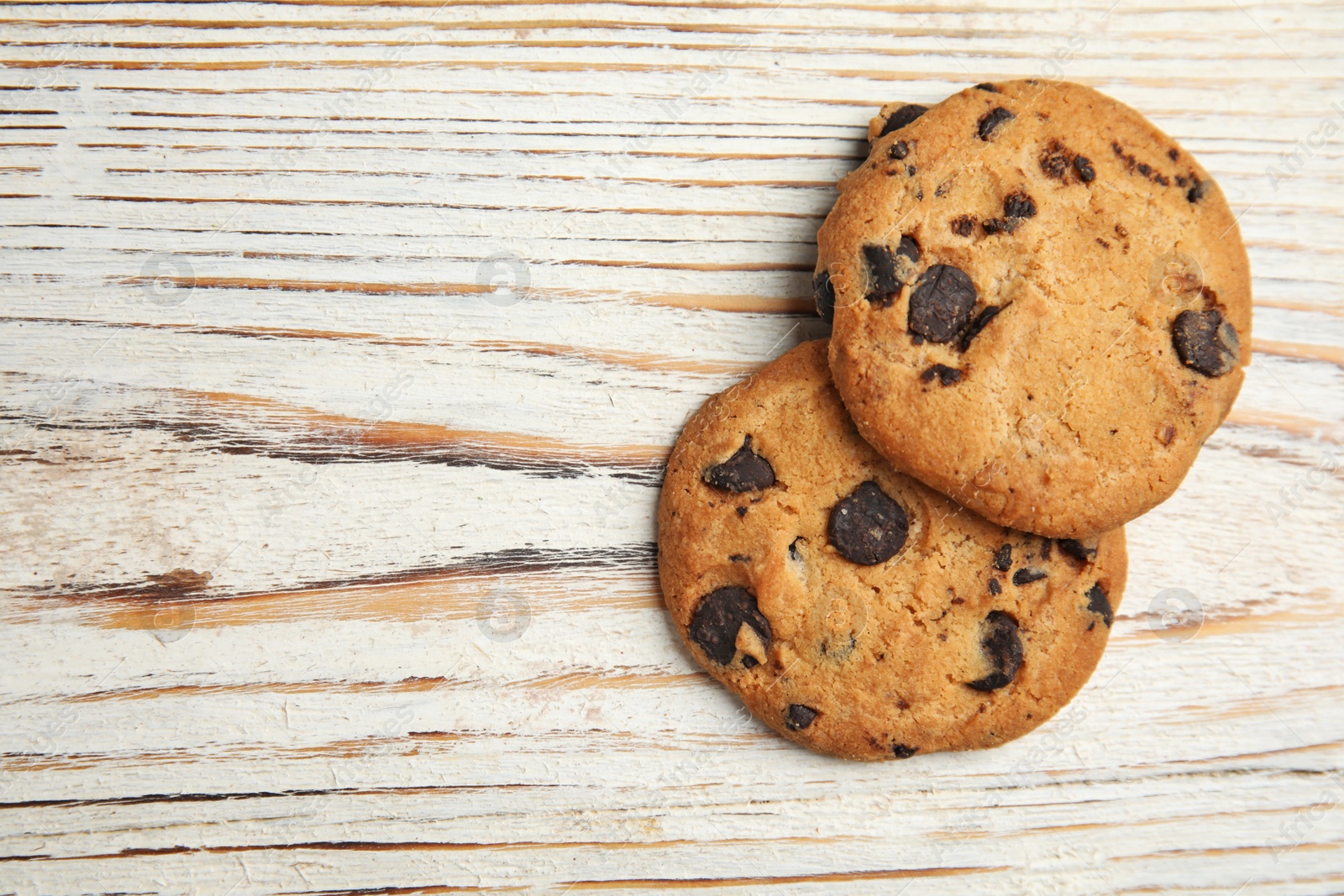 Photo of Delicious chocolate chip cookies on wooden table, flat lay. Space for text