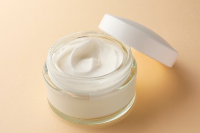 Photo of Jar of face cream on beige background, closeup