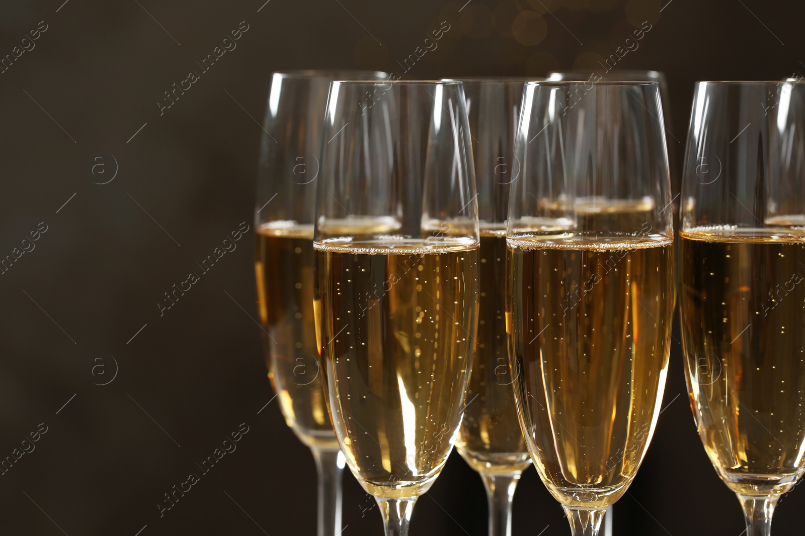 Photo of Glasses of champagne on dark background, closeup. Space for text