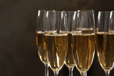 Photo of Glasses of champagne on dark background, closeup. Space for text