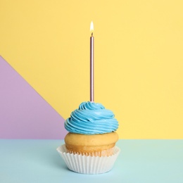 Birthday cupcake with candle on color background