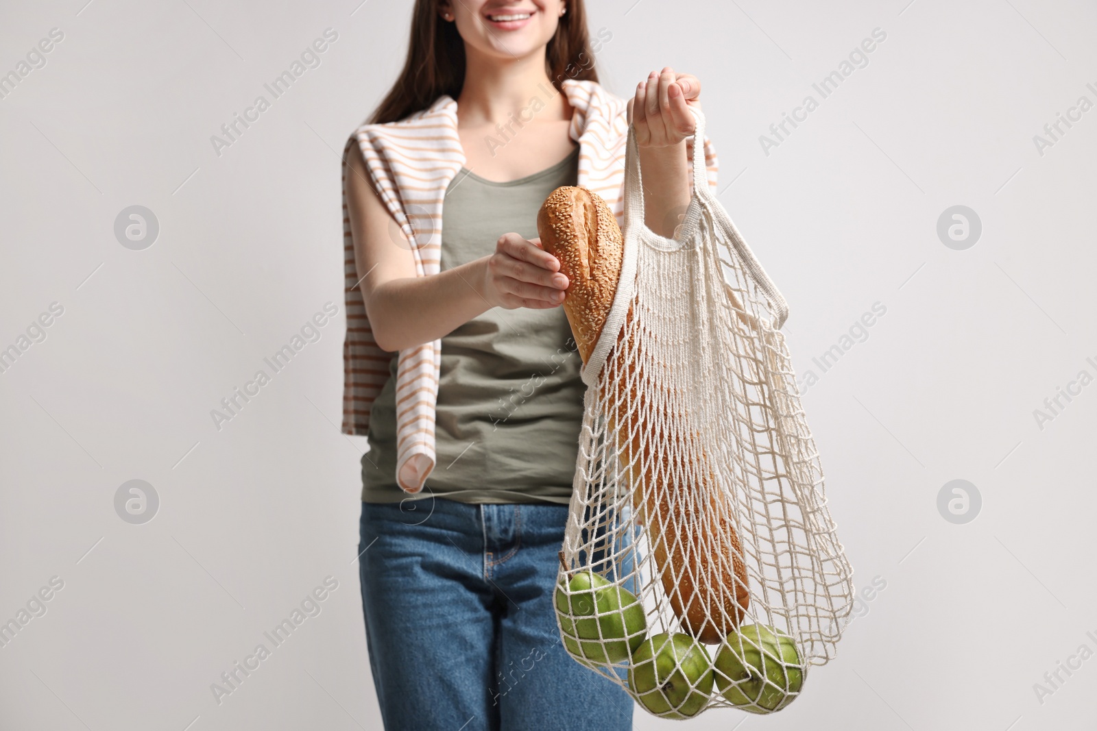 Photo of Woman with eco bag full of products on white background