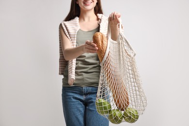 Woman with eco bag full of products on white background