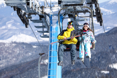 People using chairlift at mountain ski resort, space for text. Winter vacation