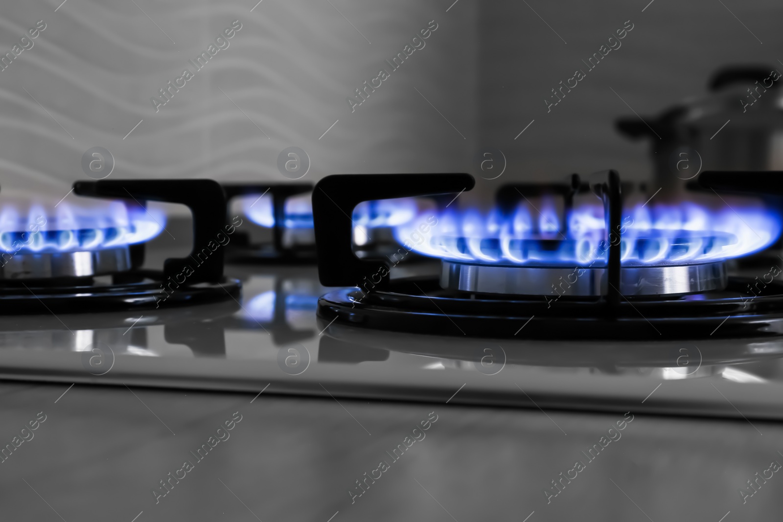 Photo of Modern gas cooktop with burning blue flames in kitchen