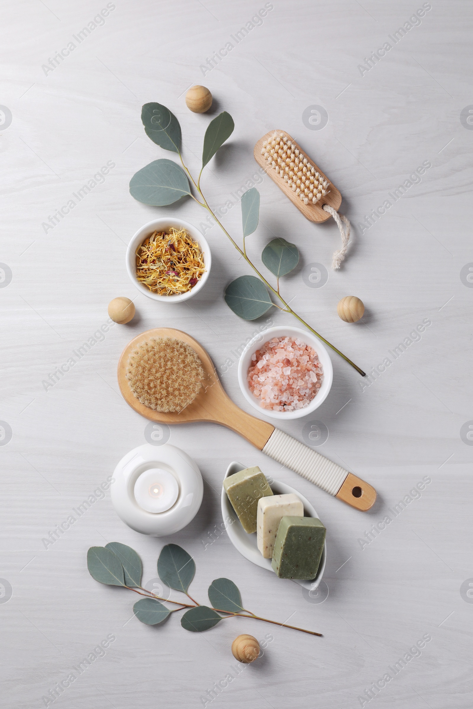 Photo of Flat lay composition with different spa products, burning candle and eucalyptus branches on light wooden table