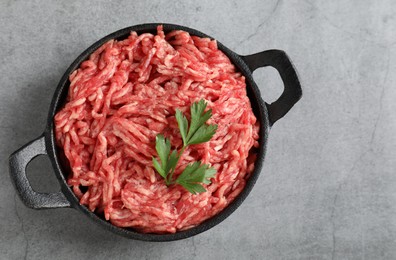 Raw ground meat and parsley in bowl on grey table, top view. Space for text