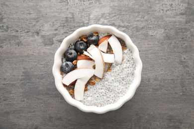 Photo of Bowl of tasty chia seed pudding with coconut, granola and blueberries on table, top view