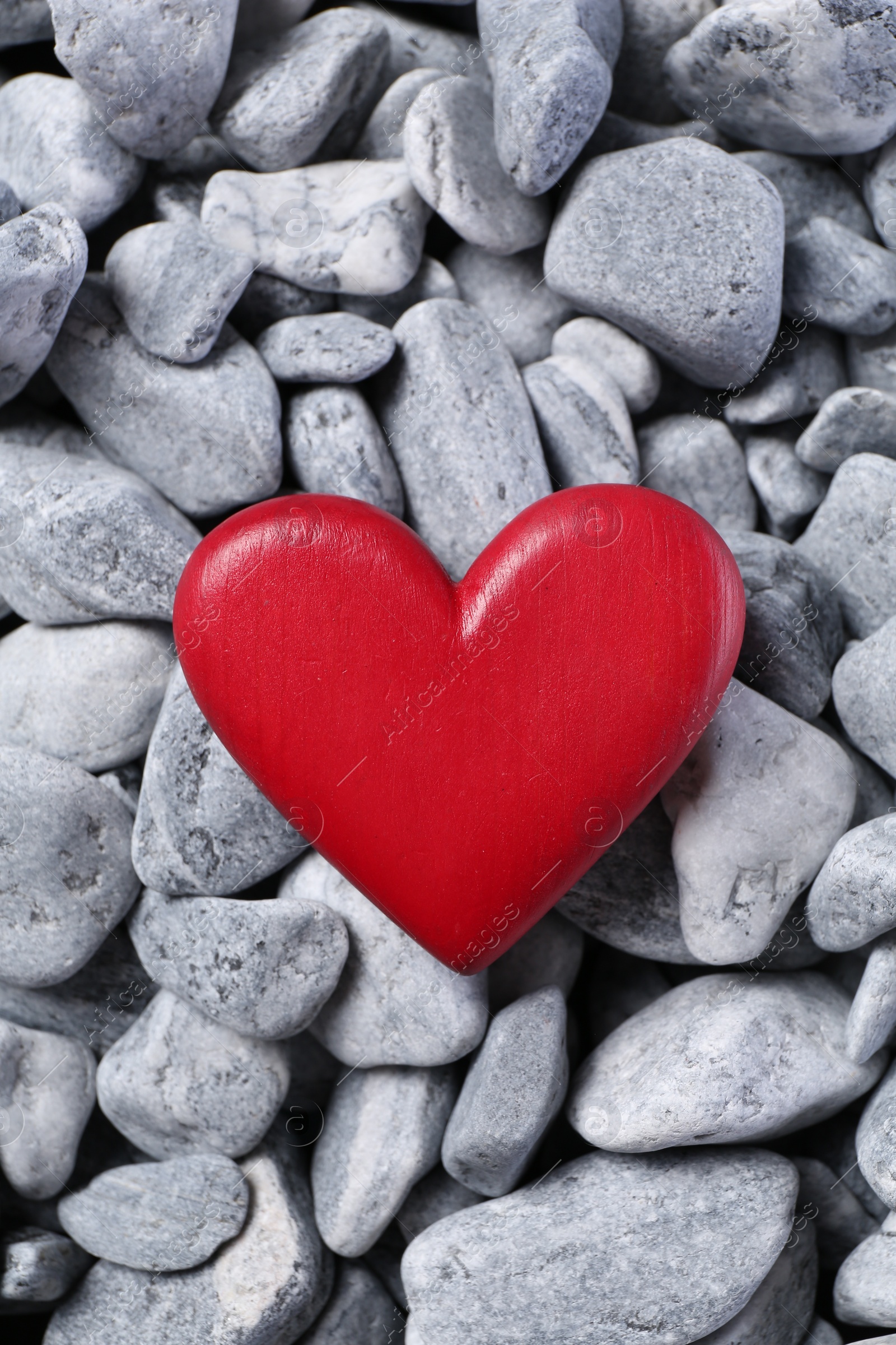 Photo of Red decorative heart on grey stones, top view