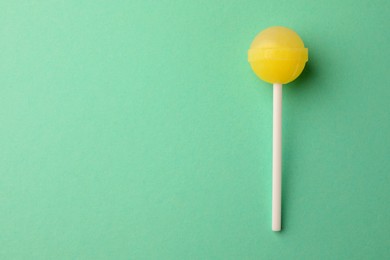 Photo of Tasty lollipop on turquoise background, top view. Space for text