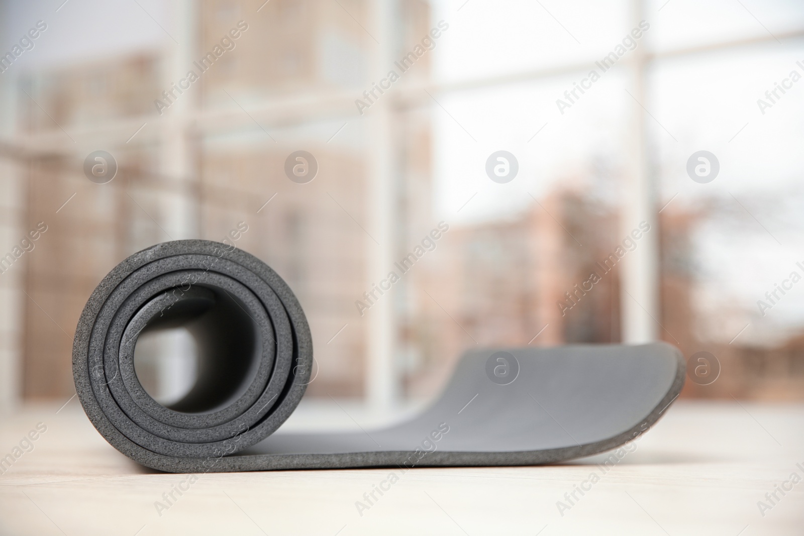 Photo of Rolled grey yoga mat on floor indoors