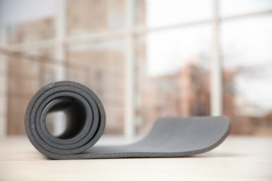 Rolled grey yoga mat on floor indoors