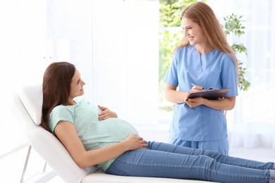 Photo of Young pregnant woman with her doctor in clinic