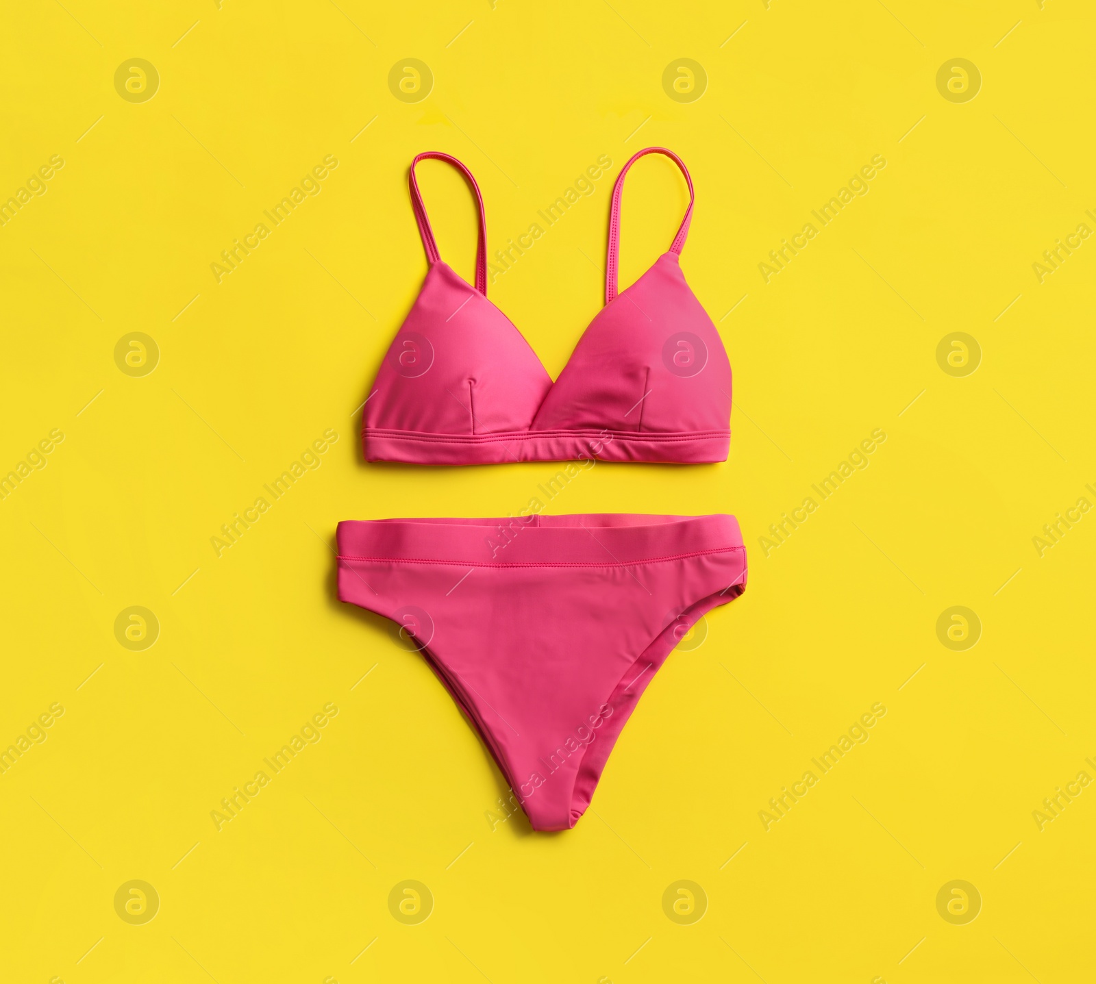 Photo of Beautiful pink bikini on yellow background, top view