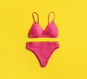 Photo of Beautiful pink bikini on yellow background, top view