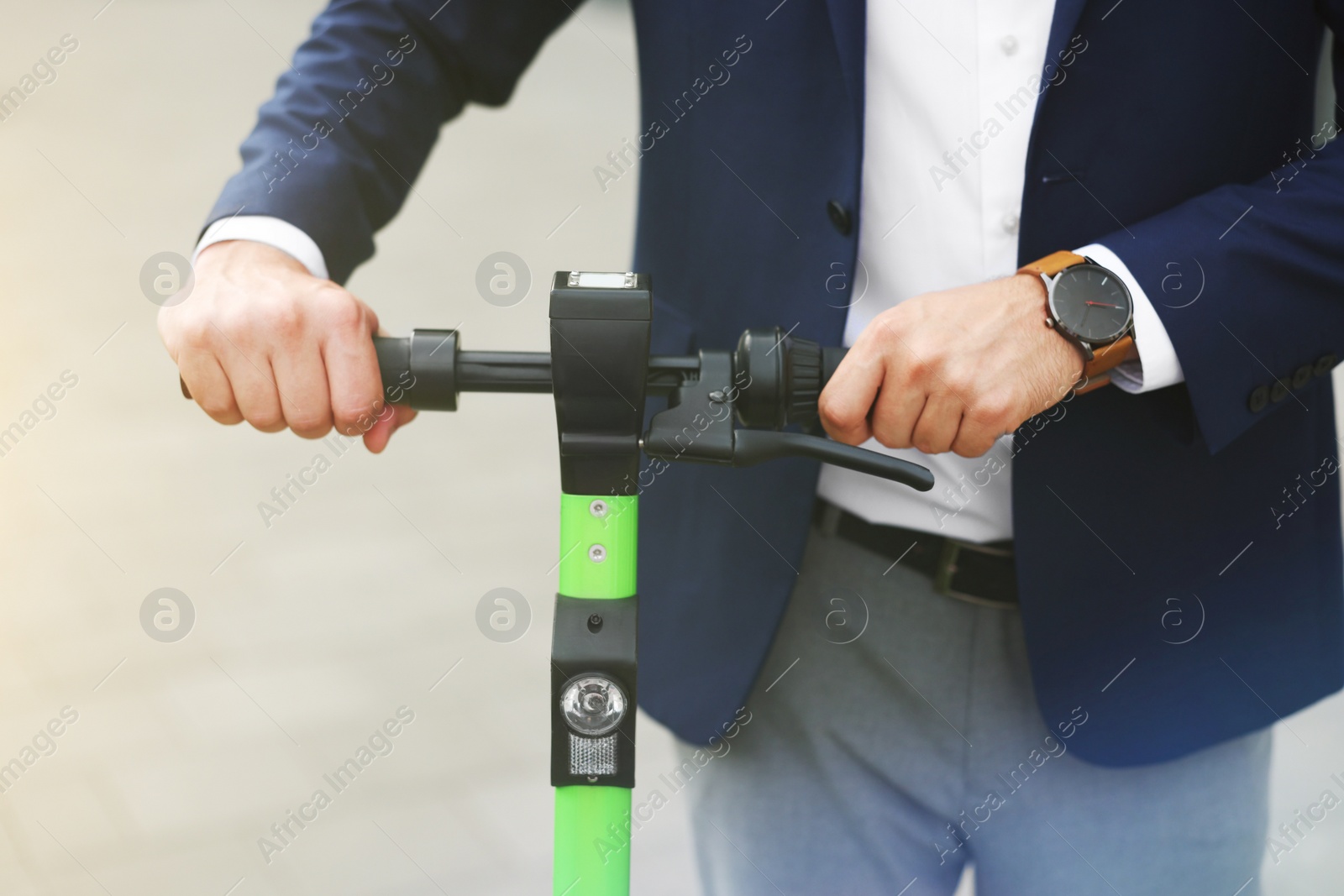 Photo of Businessman with modern kick scooter on city street, closeup