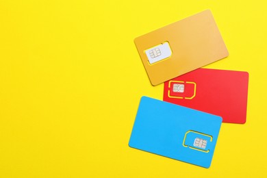 Photo of Different SIM cards on yellow background, flat lay. Space for text