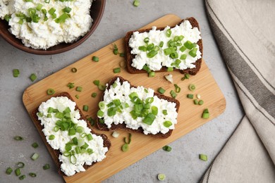 Photo of Bread with cottage cheese and green onion on light grey table, flat lay