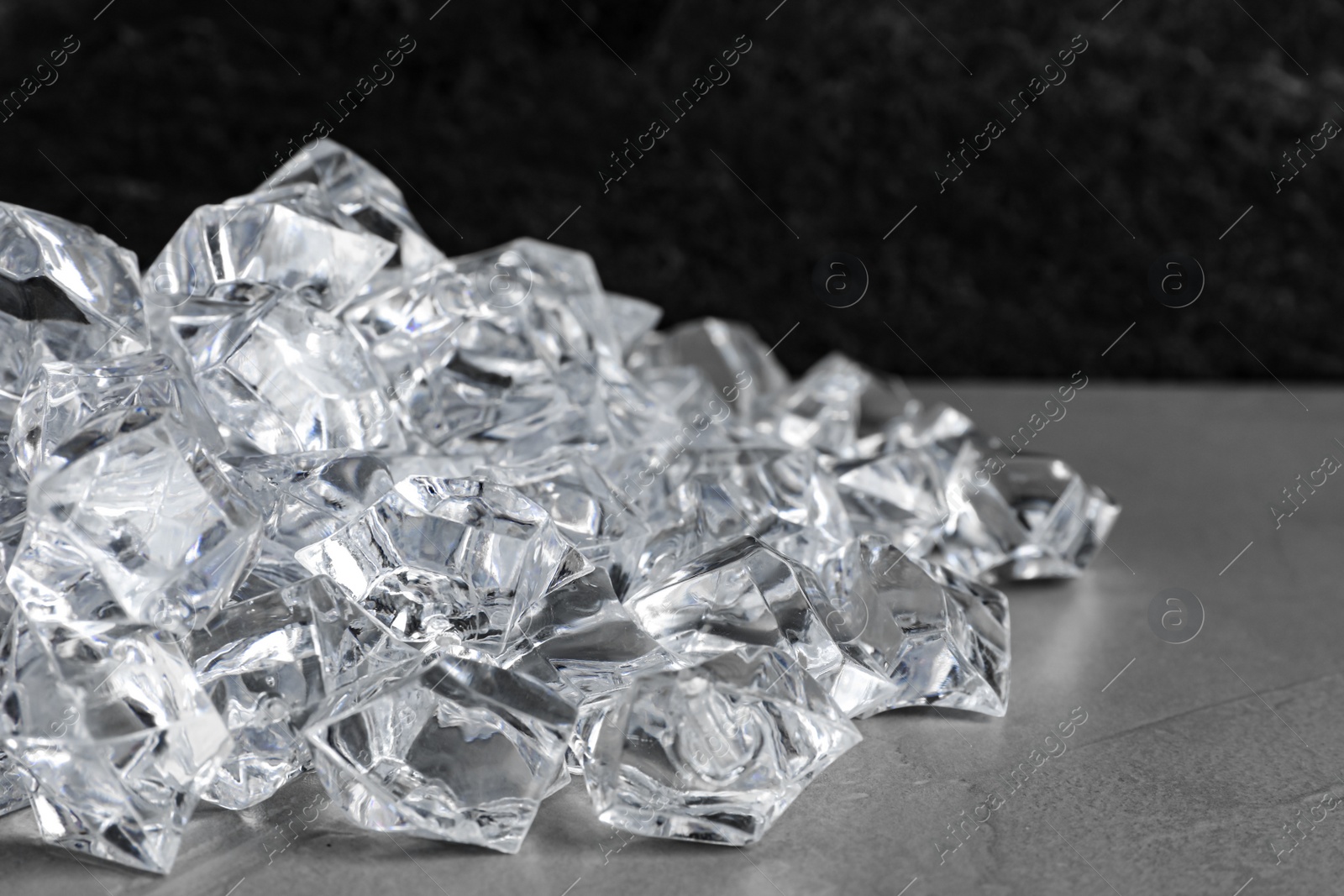 Photo of Heap of crushed ice on grey table, closeup. Space for text