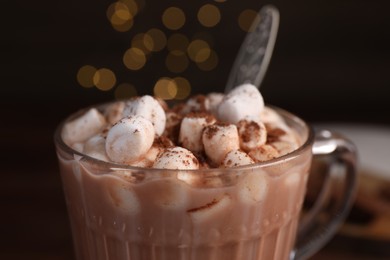 Cup of aromatic hot chocolate with marshmallows and cocoa powder on dark background, closeup