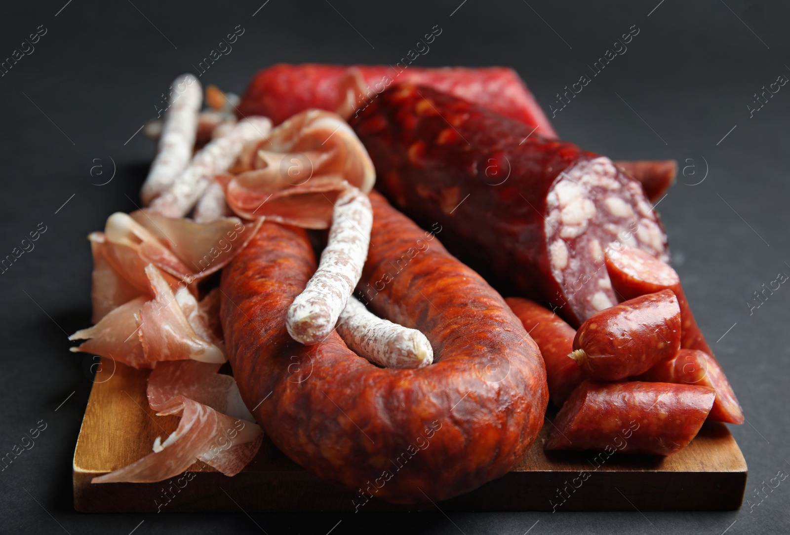 Photo of Different types of sausages served on black background, closeup