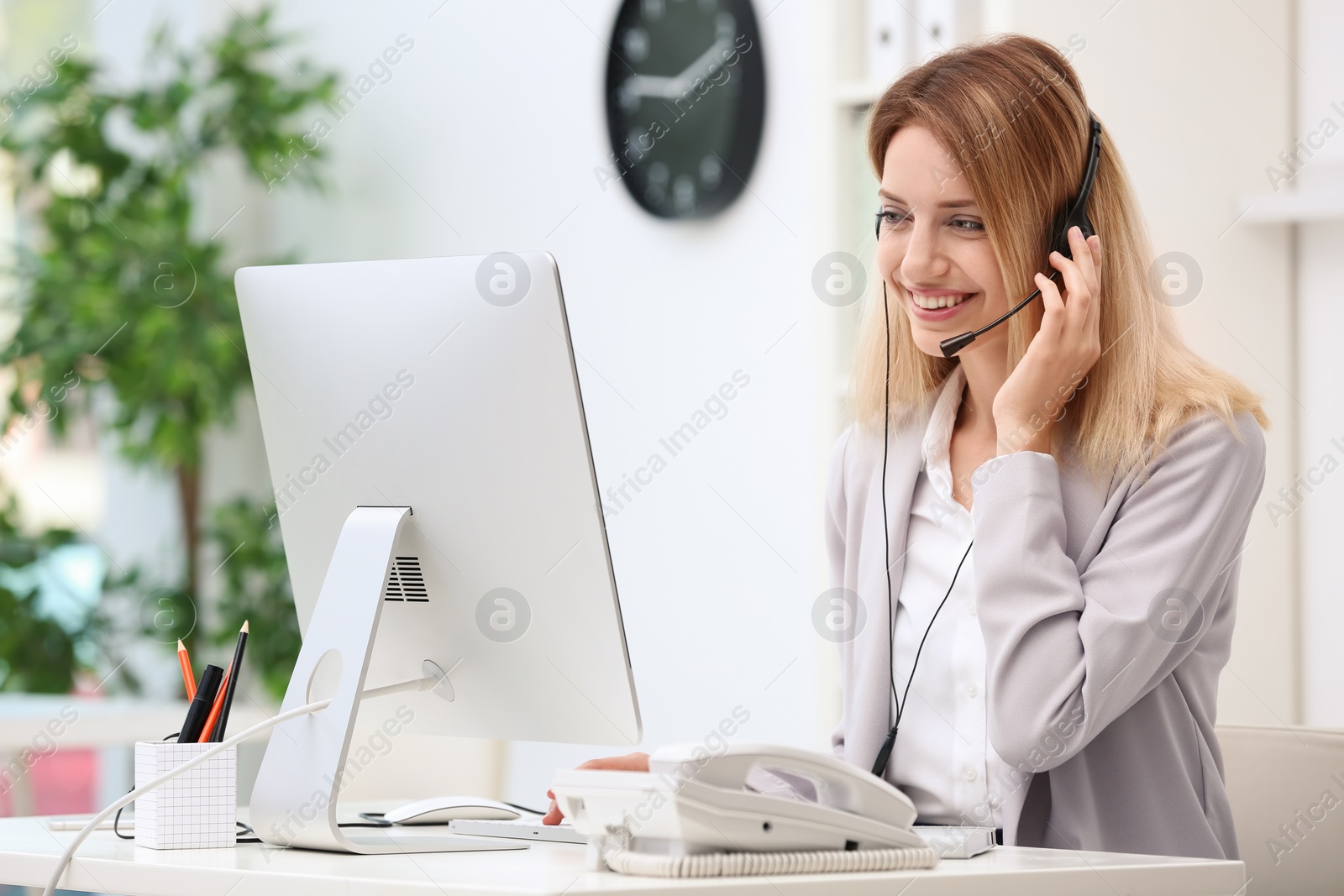 Photo of Female receptionist with headset at desk in office